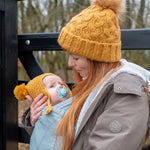 Close up of woman holding her baby in the close caboo organic baby carrier in the sage colour