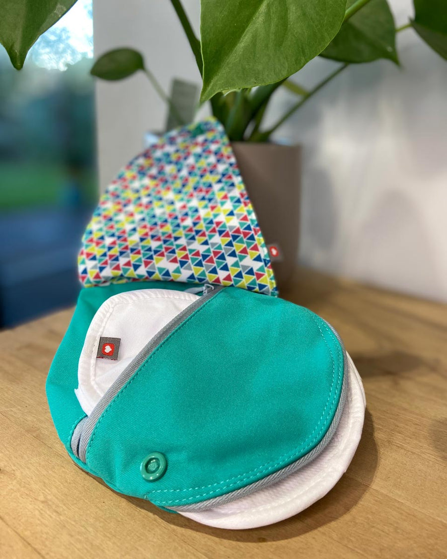 Close eco-friendly breast feeding pad pouch on a wooden table in front of a green plant