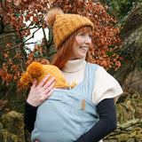 Close up of woman carrying a baby in the close organic caboo baby carrier in the sage colour