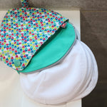 Close white breast pads on a white sink next to the Close eco-friendly brights print pad pouch