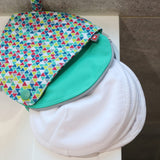 Close white breast pads on a white sink next to the Close eco-friendly brights print pad pouch