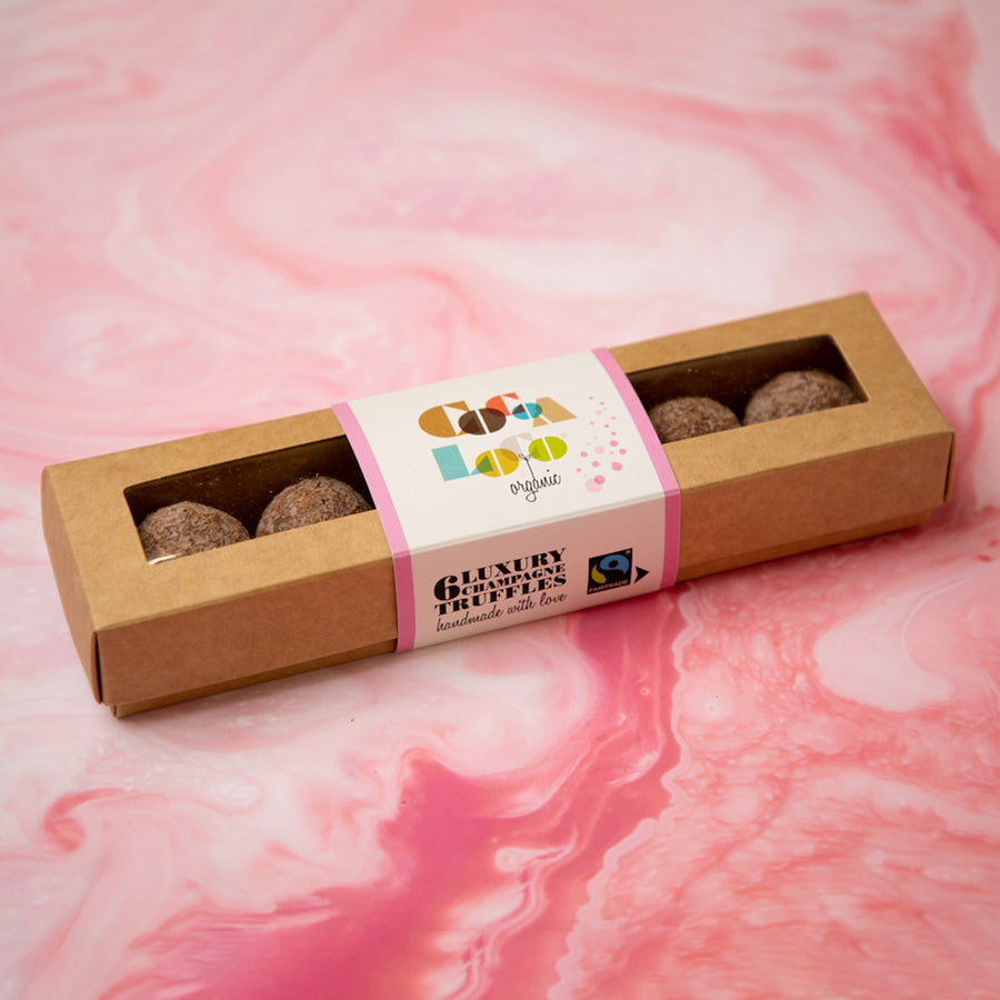 Cocoa Loco Organic Fairtrade milk chocolate champagne truffles box on a pink background