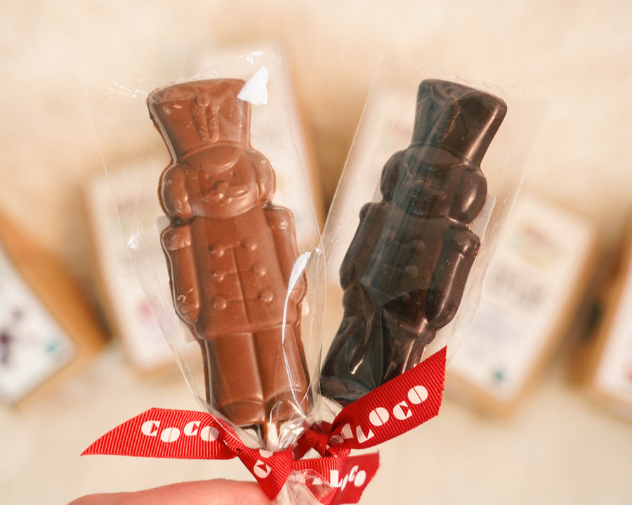 Close up of hand holding the Cocoa Loco fairtrade Christmas soldier lollies in front of some Cocoa Loco chocolate boxes.