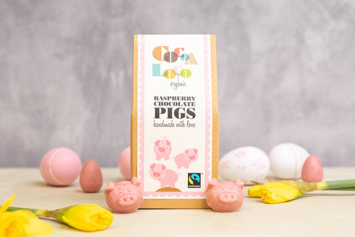 Cocoa Loco eco-friendly raspberry chocolate pigs on a cream worktop next to some pink and white easter eggs and daffodils