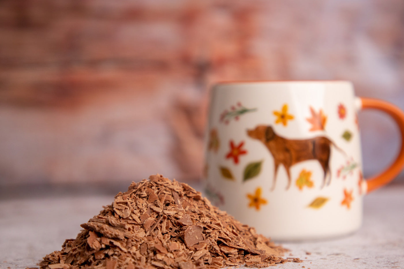 Close up of some Cocoa Loco fairtrade hot chocolate drinking flakes in a pile in front of a white and orange mug