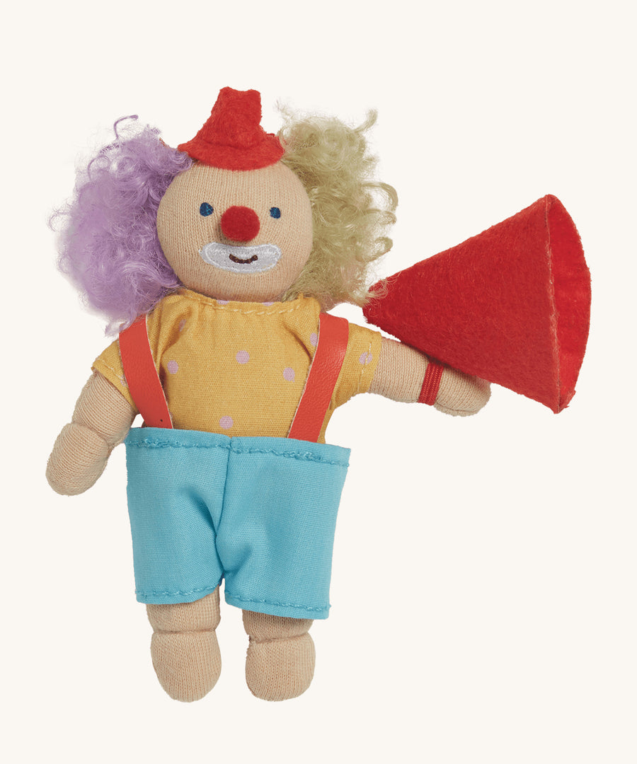 Olli Ella Holdie Folk Confetti The Clown. A fun clown figure with purple and blonde hair, a little red hat, a yellow top with white spots and light blue shorts, with a red fabric megaphone, on a cream background