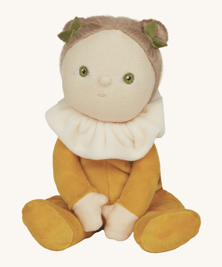 Olli Ella Cora Corn in a velvet yellow outfit, plush peach collar, white skin, green eyes, light hair tied up with little green leaf hair accessory, on a cream background