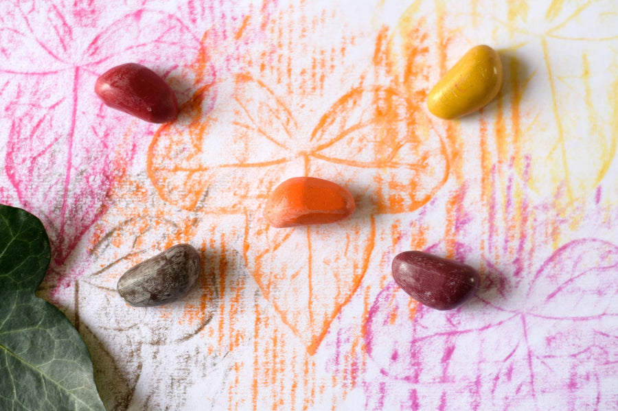 Close up of some coloured Crayon Rocks on top of a leaf rubbing on some white paper