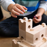 Close up of child holding a green glass marble above the Cuboro handmade wooden marble run building blocks