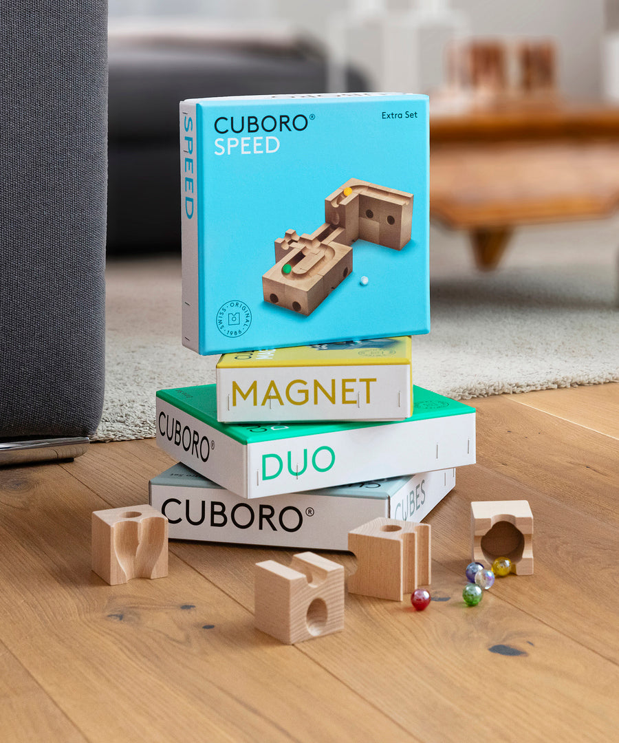 Cuboro plastic-free wooden marble run sets stacked on a wooden floor