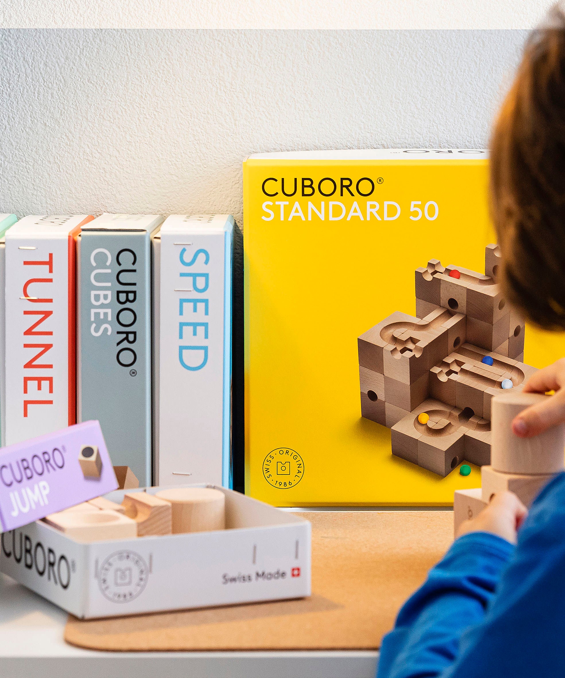 A close up of a child playing with the Cuboro wooden jump marble set. 