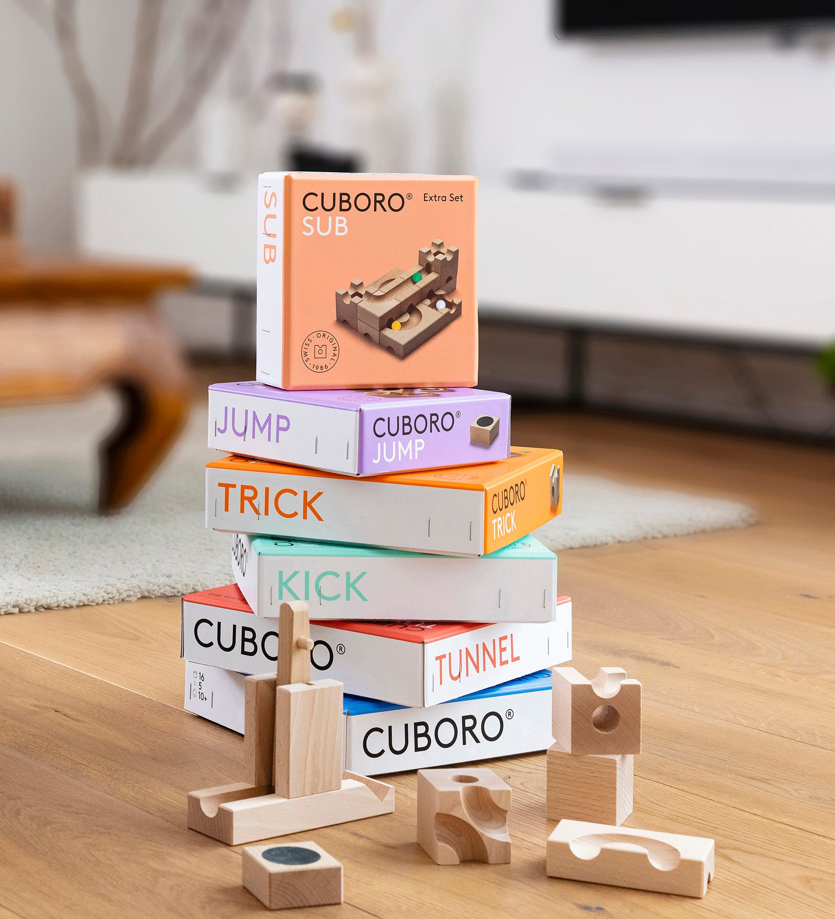 A stack of different Cuboro sets with pieces of the jump and kick sets on a wooden floor.