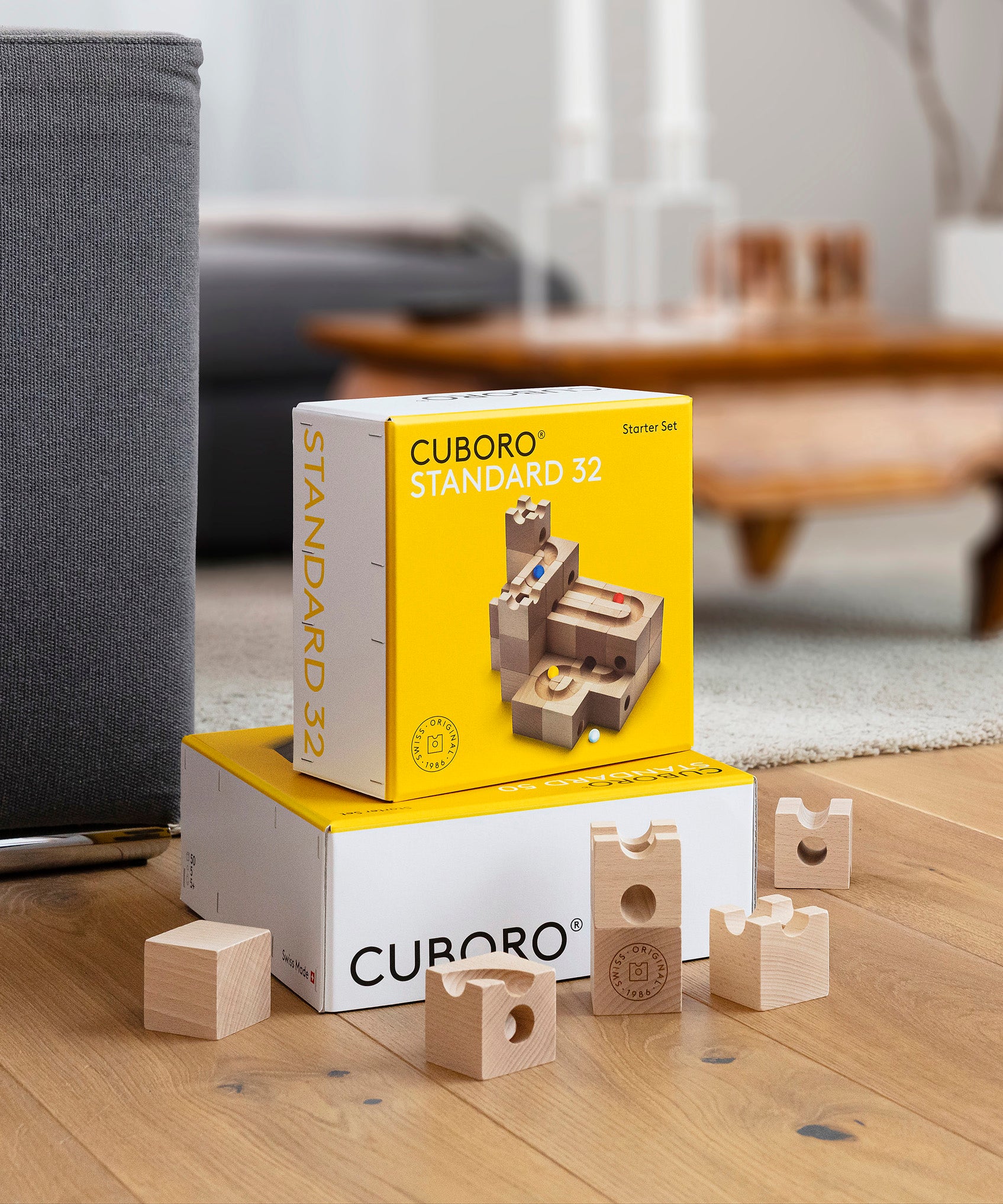 Cuboro standard wooden marble run kits stacked in piles on a wooden floor