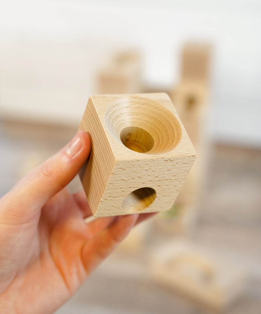 A close up of a wooden block from a Cuboro wooden marble set.