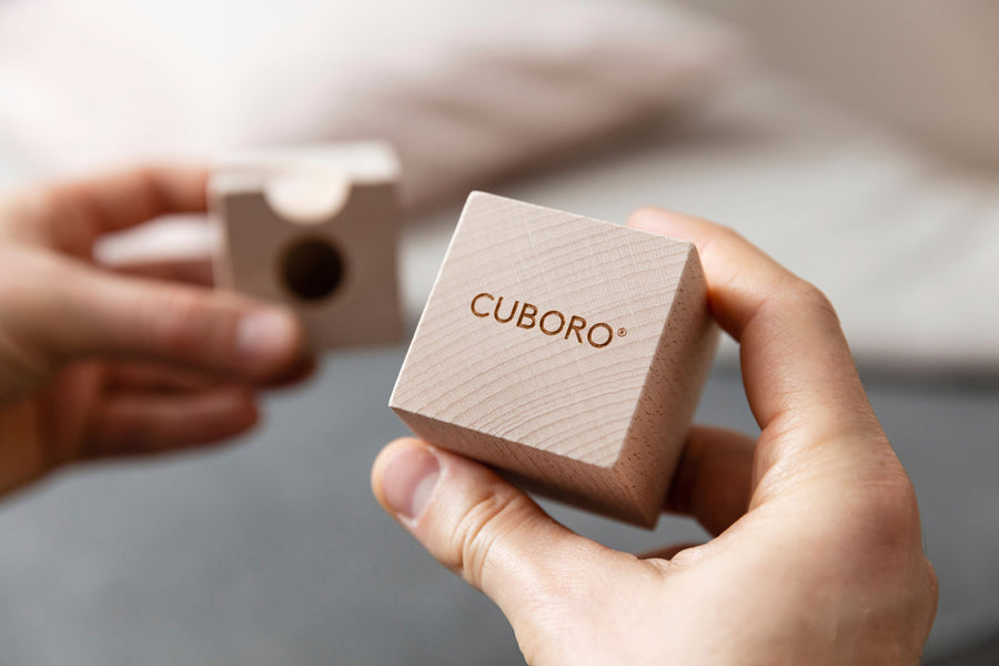 A hand holding a branded wooden cuboro block