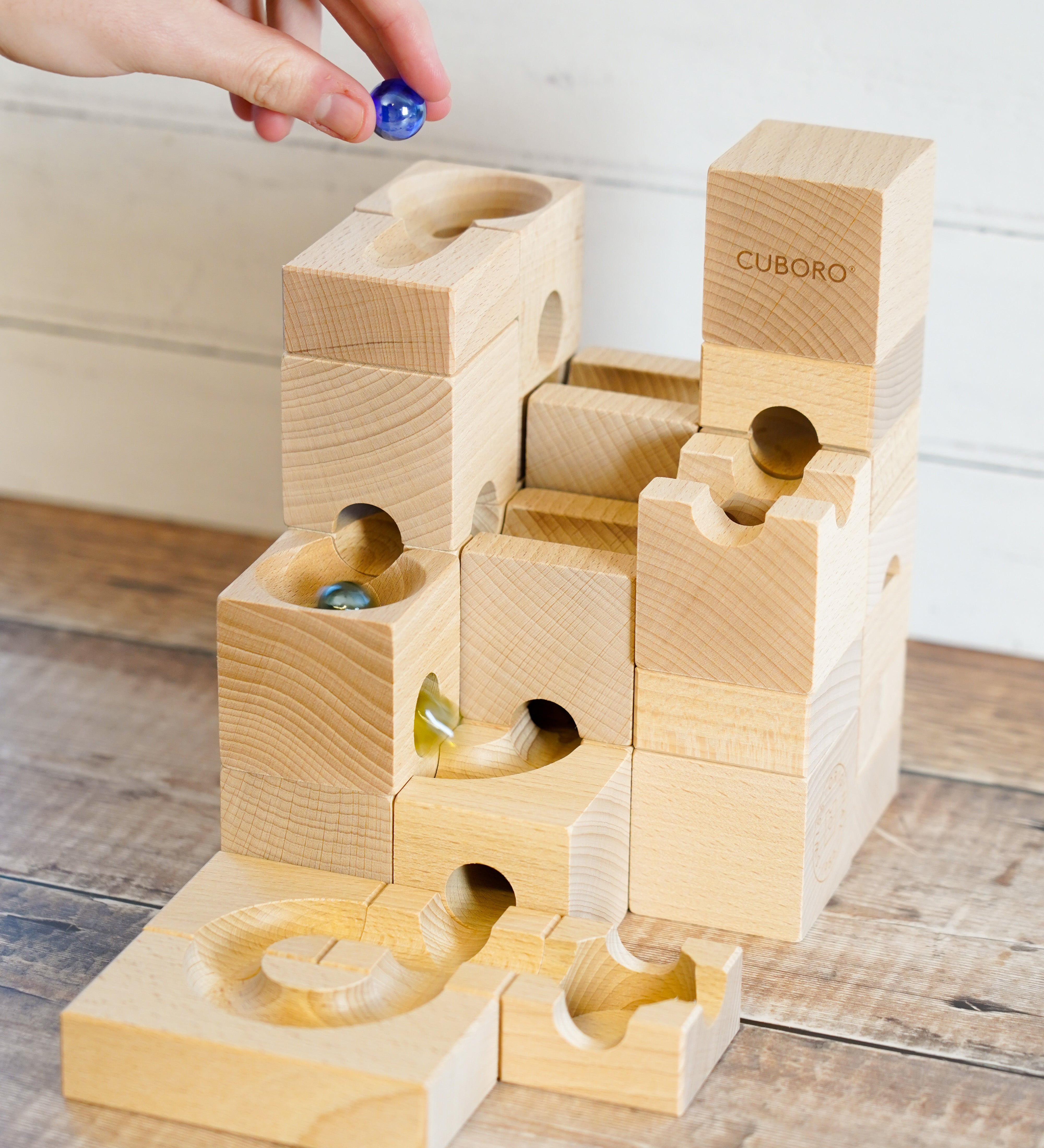 A Cuboro wooden standard marble run with marbles running on it on a wooden floor