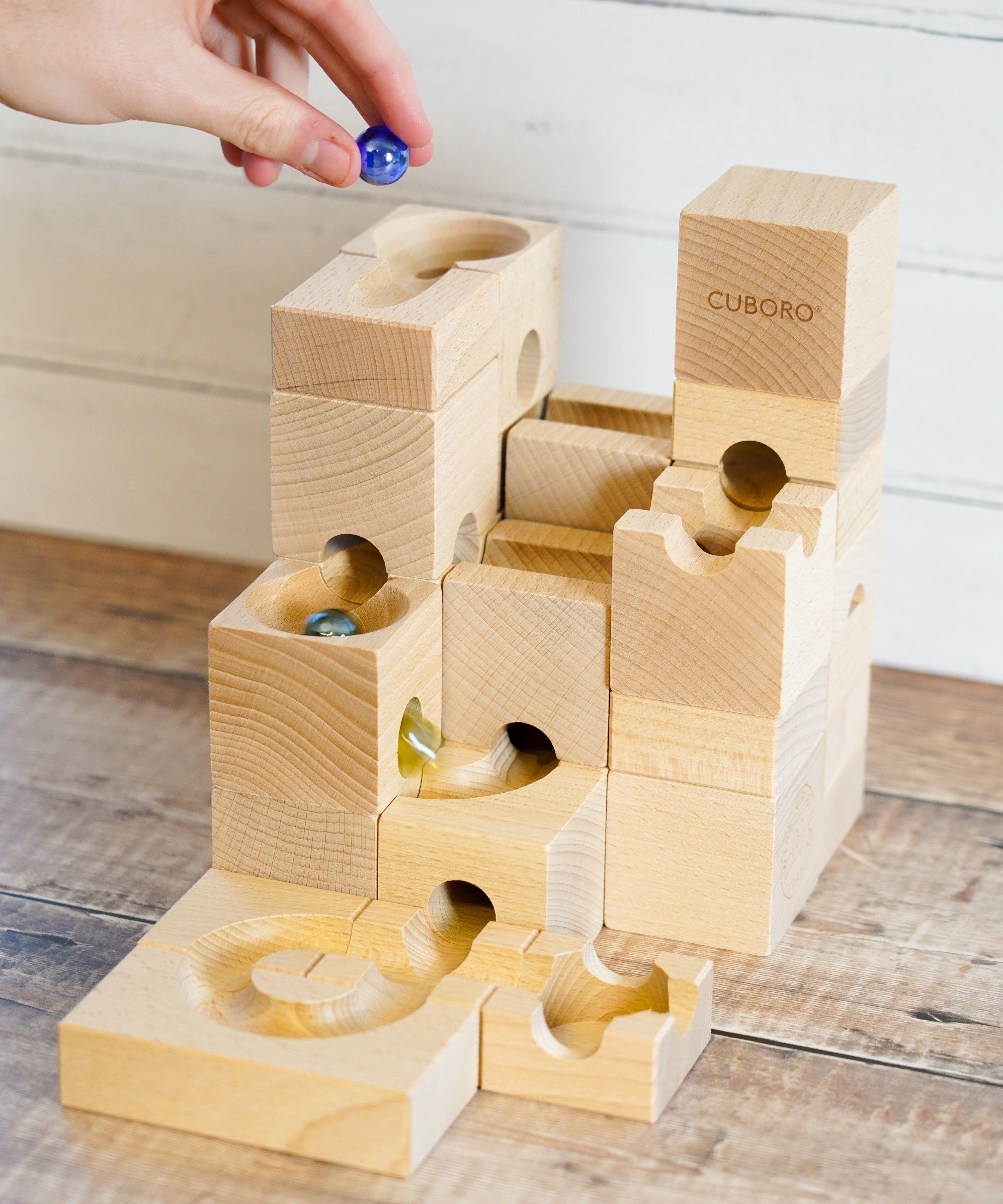 A Cuboro wooden standard marble run with marbles running on it on a wooden floor