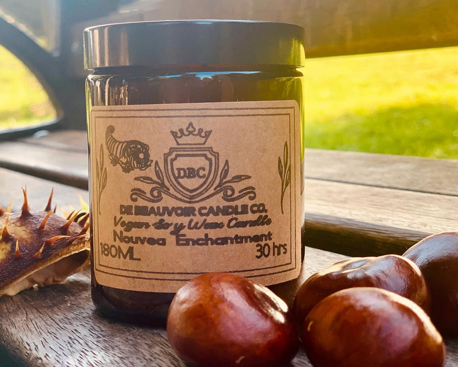 De Beauvoir 180ml scented candle on a wooden bench next to some conkers