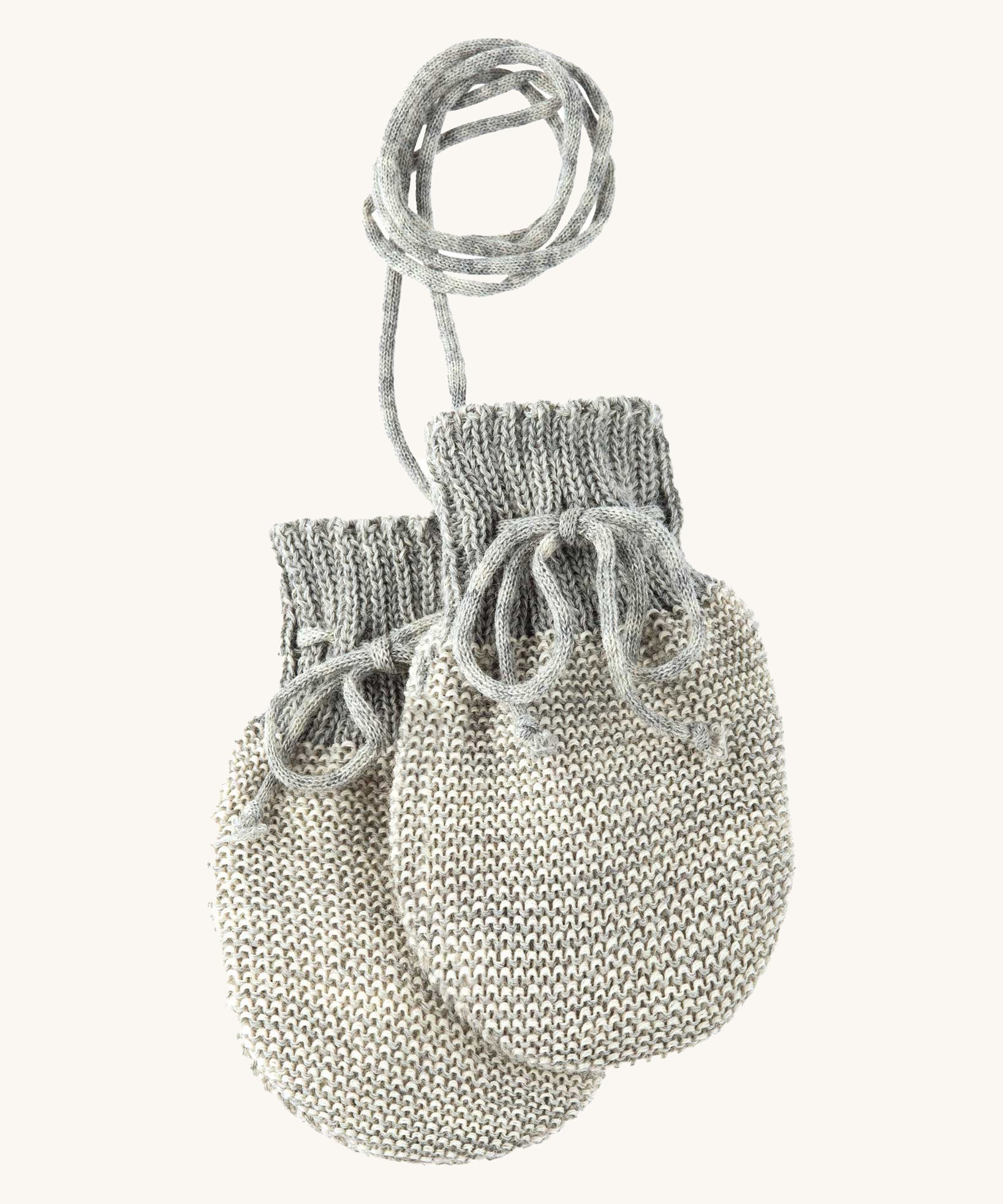 Disana organic merino wool baby mittens in grey and natural colour on a cream background.