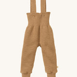 Disana organic merino wool dungarees in light brown on a cream background.