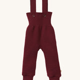 Disana organic merino wool dungarees in dark purple on a cream background.