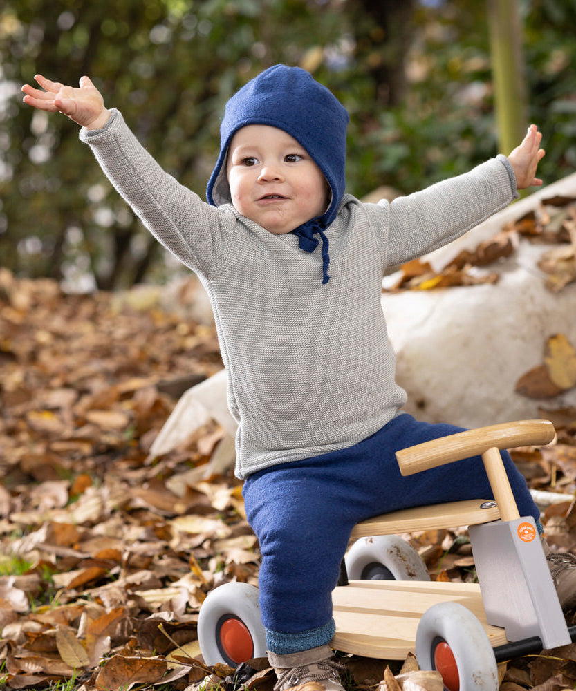 Disana organic merino wool melange jumper in a grey colour worn by a toddler playing on a toy bike