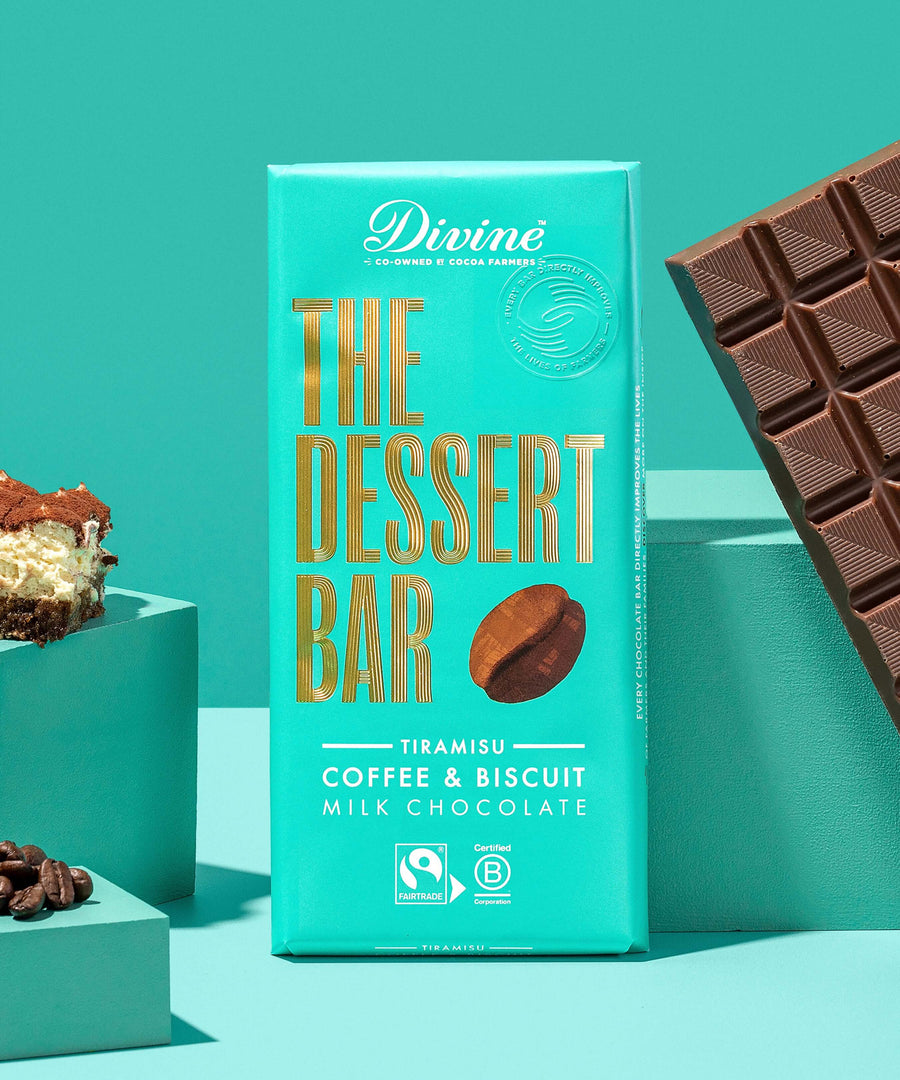 The Divine Tiramisu Dessert Bar shown in it's wrapping. An unwrapped bar can be seen on one side with a piece of tiramisu and coffee beans on the other side. 