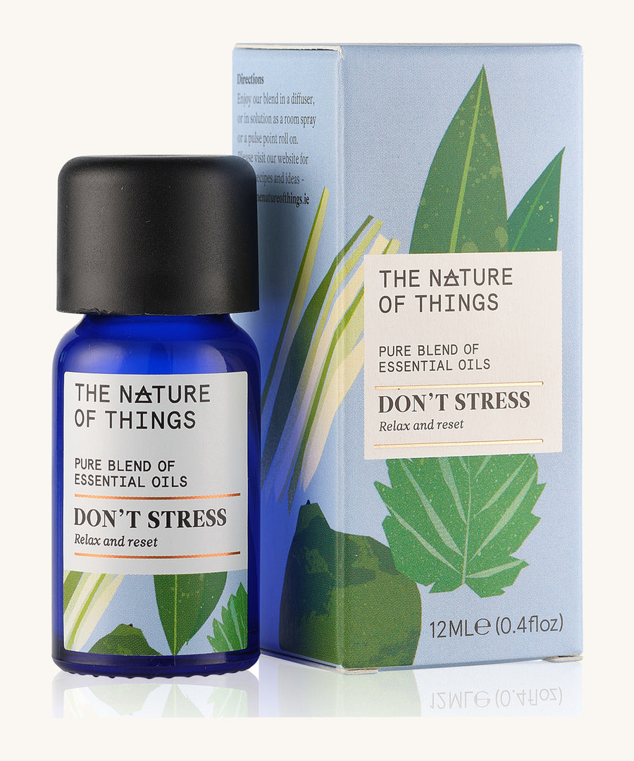 Don't Stress pure essential oil blend  in a blue glass bottle in front of a decorative blue cardboard box.