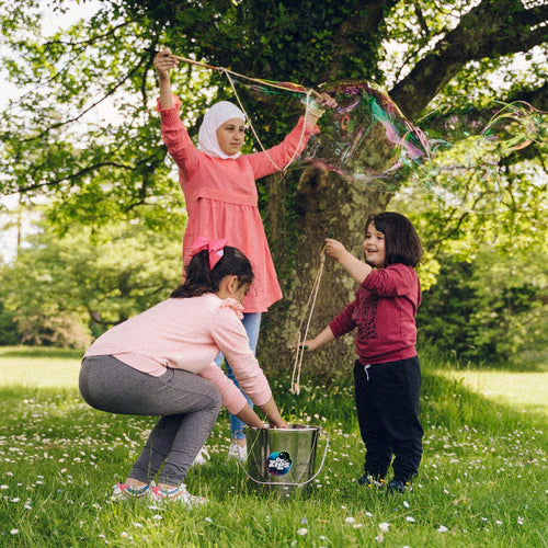 3 people making bubbles outdoors using the Dr Zigs metal stainless bucket