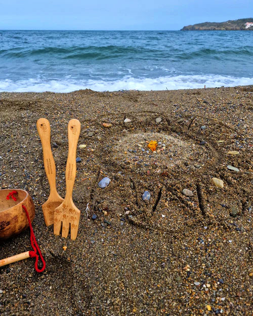 A mandala shape in the sand created using the bamboo tools for the Dr Zigs beach creativity set. The Kit is placed beside the mandala on the sand