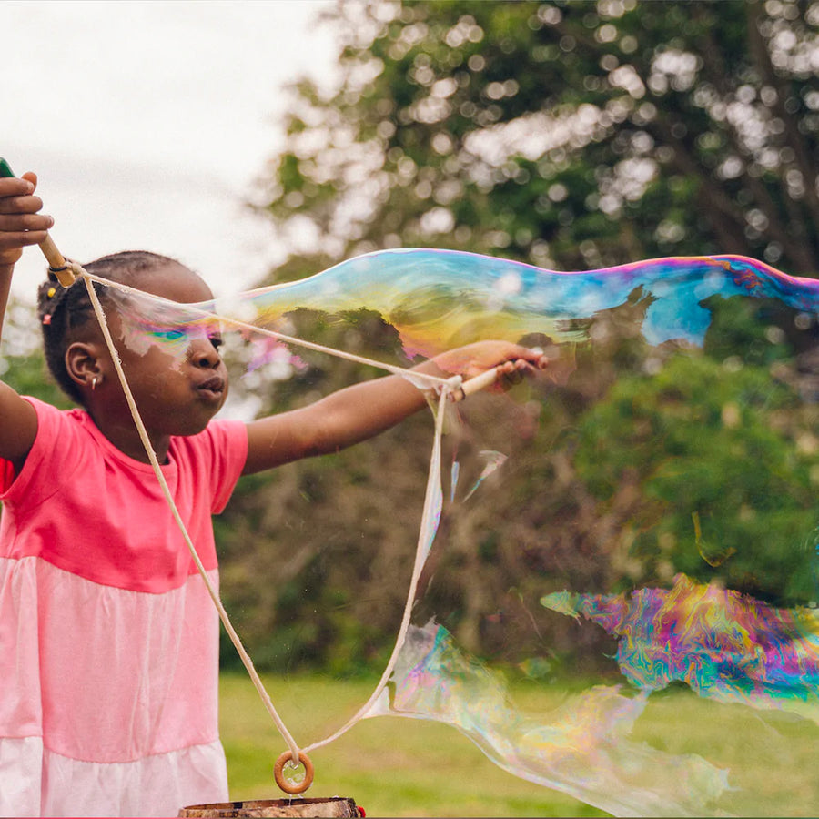 Girl blowing giant bubble from the Dr Zigs eco-friendly giant bubble travel kit wand