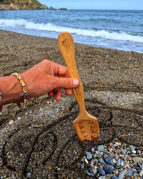 The bamboo spade from the Dr Zigs Beach Creativity Kit being used on a beach to create a mandala shape in the sand