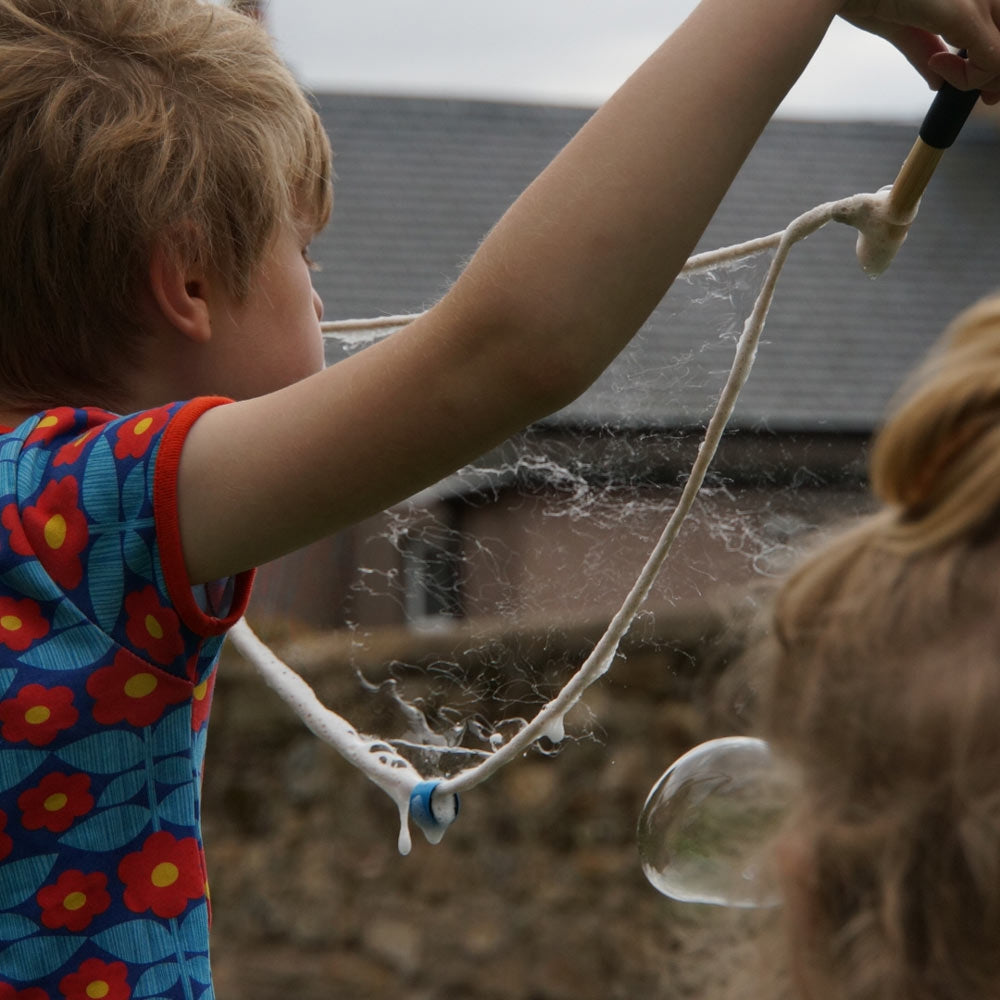 Close up of boy holding up the giant Dr Zigs bubble wand to blow a bubble