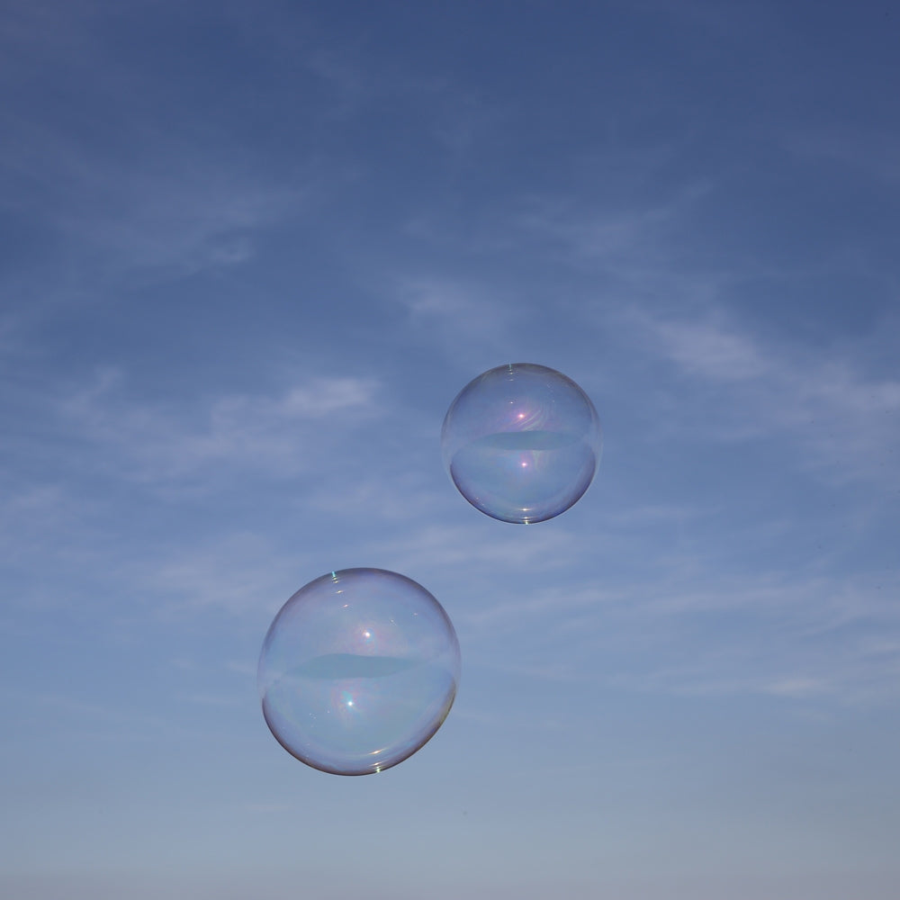 Close up of two Dr Zigs giant eco-friendly bubbles floating in a blue sky