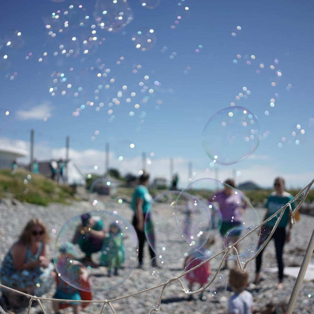 Close up of bubbles floating out from the Dr Zigs multi bubble wand over a pebble beach