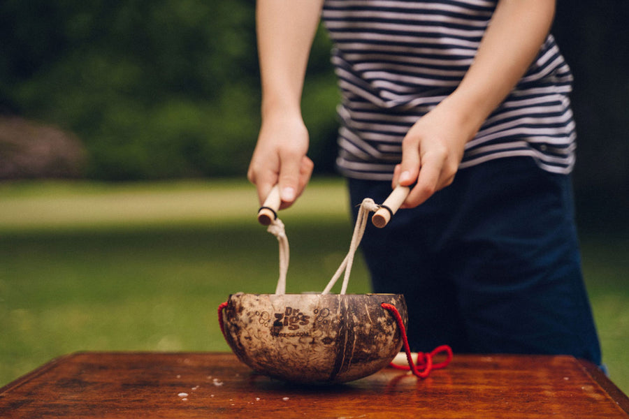 Close up of some childs hands playing with the Dr Zigs coconut bubbles kit outdoors in a large field