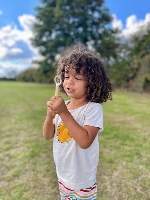 Child blowing bubbles with the small hand wand from the mini bubble kit