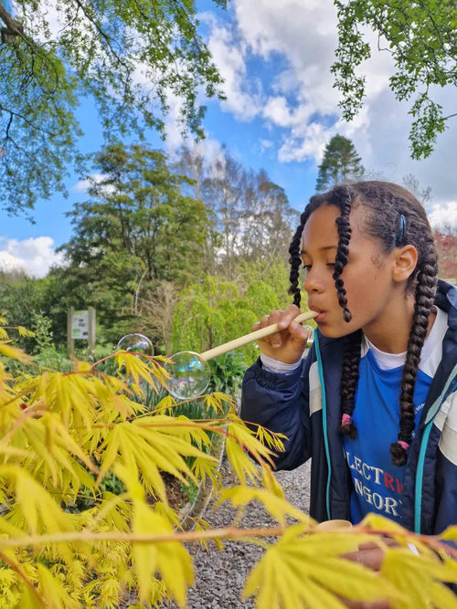 Child using the straw from the Dr Zigs bubble pollinator kit