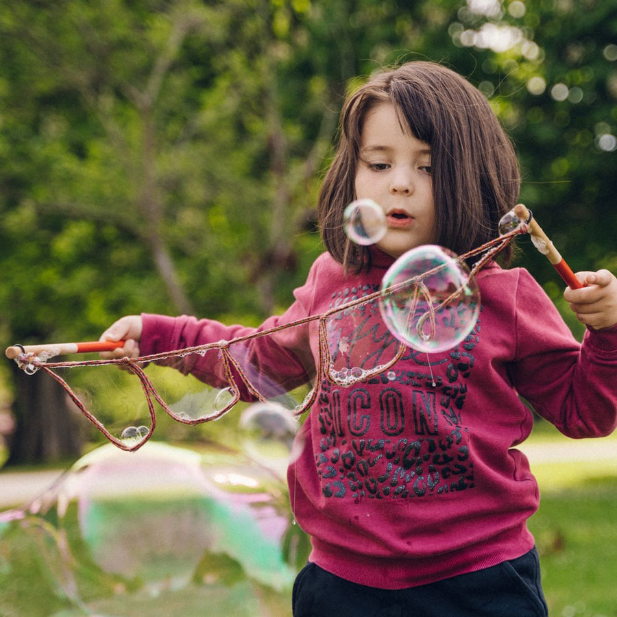 Child using the Dr Zigs Mini Multi-Loop Lots of Bubbles Wand - 40cm in a park