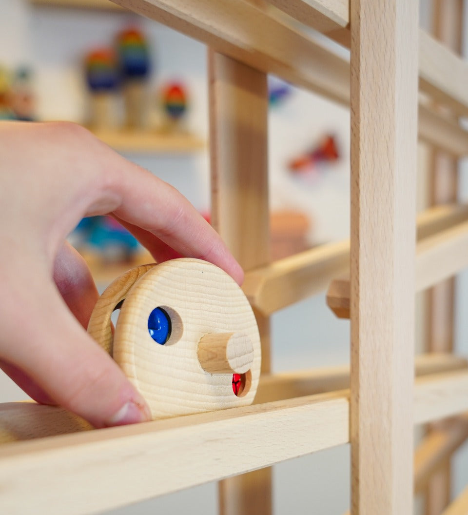 Close up of a hand placing the Fagus wooden bell disc toy on a Fagus marble run set