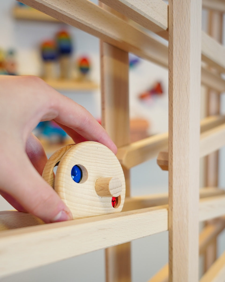 Close up of a hand placing the Fagus wooden bell disc toy on a Fagus marble run set