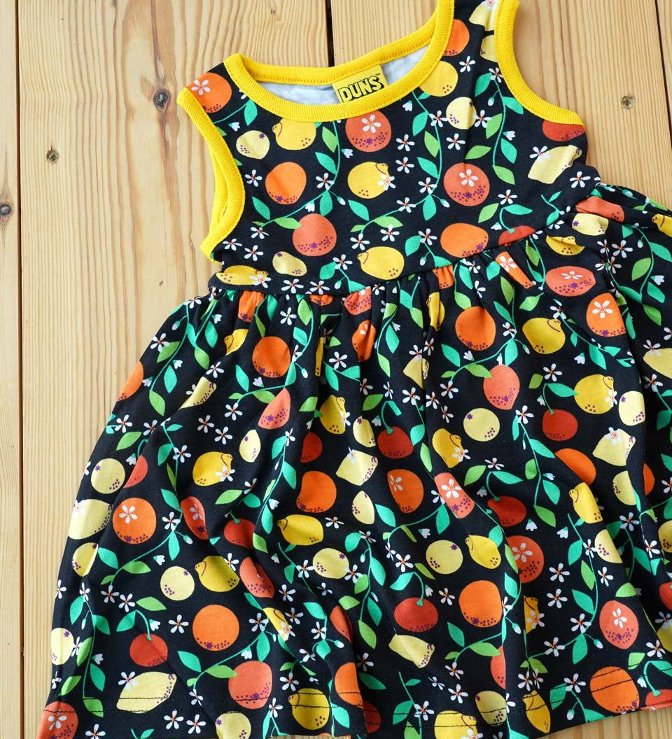 Close up of the DUNS Sweden organic cotton black citrus sleeveless gather skirt dress on a wooden floor