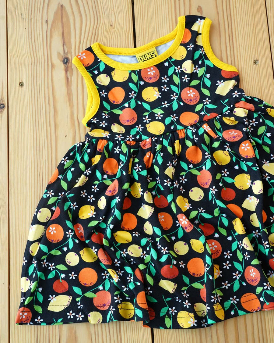 Close up of the DUNS Sweden organic cotton black citrus sleeveless gather skirt dress on a wooden floor