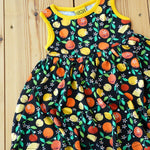 Close up of the DUNS Sweden organic cotton black citrus sleeveless gather skirt dress on a wooden floor