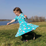 Girl running on some grass wearing the DUNS Sweden organic cotton skater dress in the blue puffin print