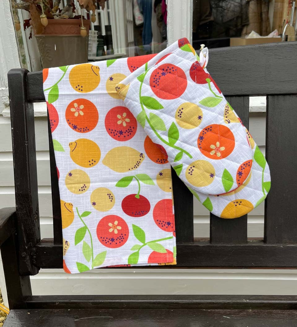 DUNS eco-friendly organic cotton oven glove and tea towel in the citrus print hanging over the end of a black bench