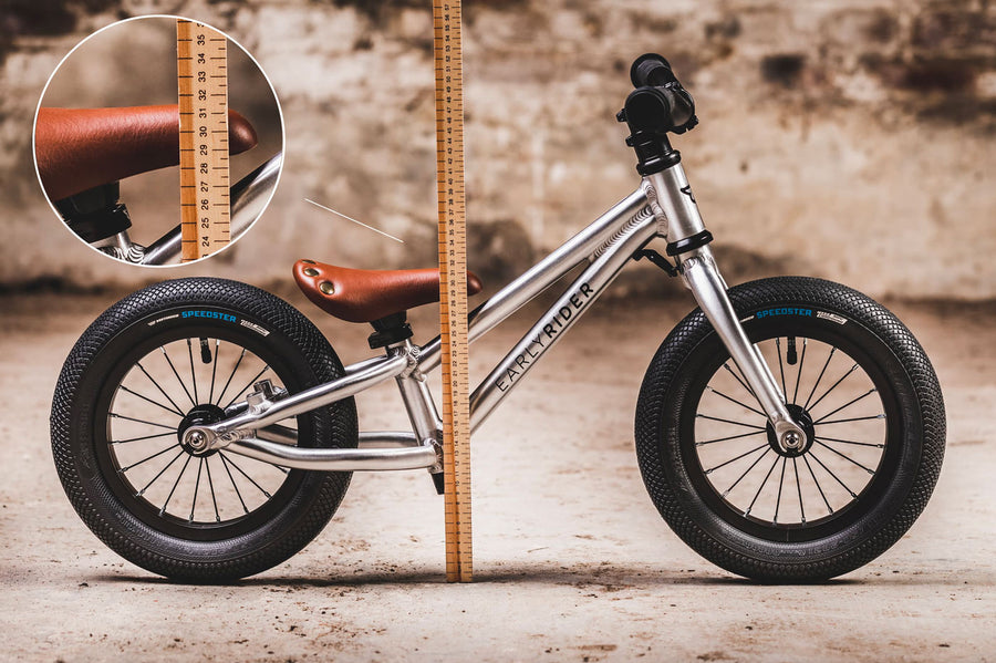 Close up of a child walking next to an Early rider charger balance bike