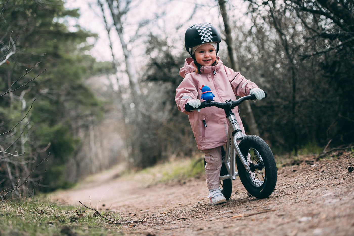 Close up of a child walking next to an Early rider charger balance bike