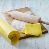 Ecoliving yellow compostable sponge kitchen roll next to a wooden board and rolling pin