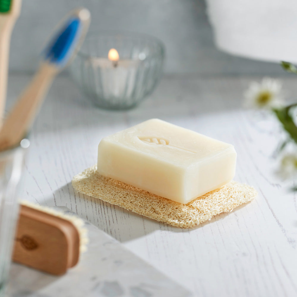 Eco Living plastic free reusable loofah soap bard pad on a white work top with a soap bar on top